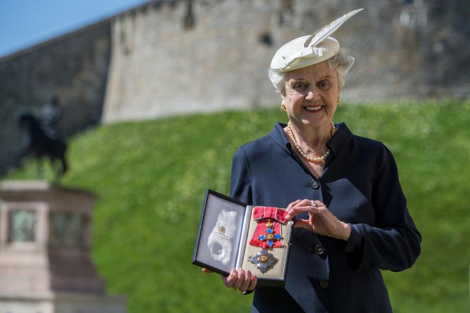 Angela Lansbury poses with her Dame Commander (DBE) medal given to her by Queen Elizabeth II at an Investiture ceremony at Windsor Castle