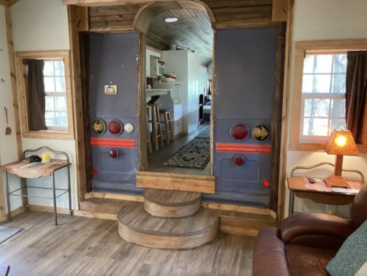 Bluebird Nest Interior: living room with doorway made of the back of the bus leading into the kitchen