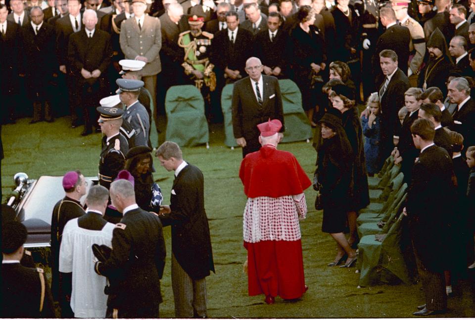 Jacqueline Kennedy carries the American flag that had draped her husband's coffin at Arlington National Cemetery.