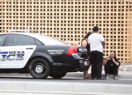 Tanya Ehrig, who claimed in a TV interview that her sister's boyfriend was a victim, sits near a police car at one of the scenes of a multiple location shooting that has injured at least four people in Mesa, Arizona March 18, 2015. REUTERS/Deanna Dent