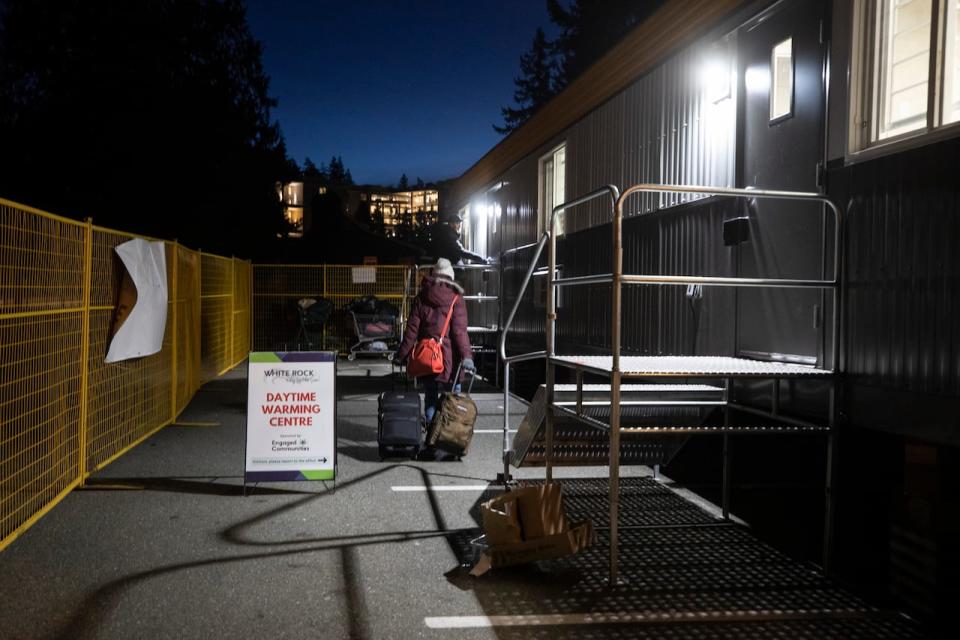 An unhoused woman walks with her belongings to the Daytime Warming Centre in White Rock, B.C. on Jan. 15, 2024.