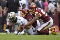 New Orleans Saints quarterback Jameis Winston is tackled by Washington Football Team linebacker Cole Holcomb (55) and defensive end Montez Sweat (90) in the first half of an NFL football game, Sunday, Oct. 10, 2021, in Landover, Md. (AP Photo/Al Drago)