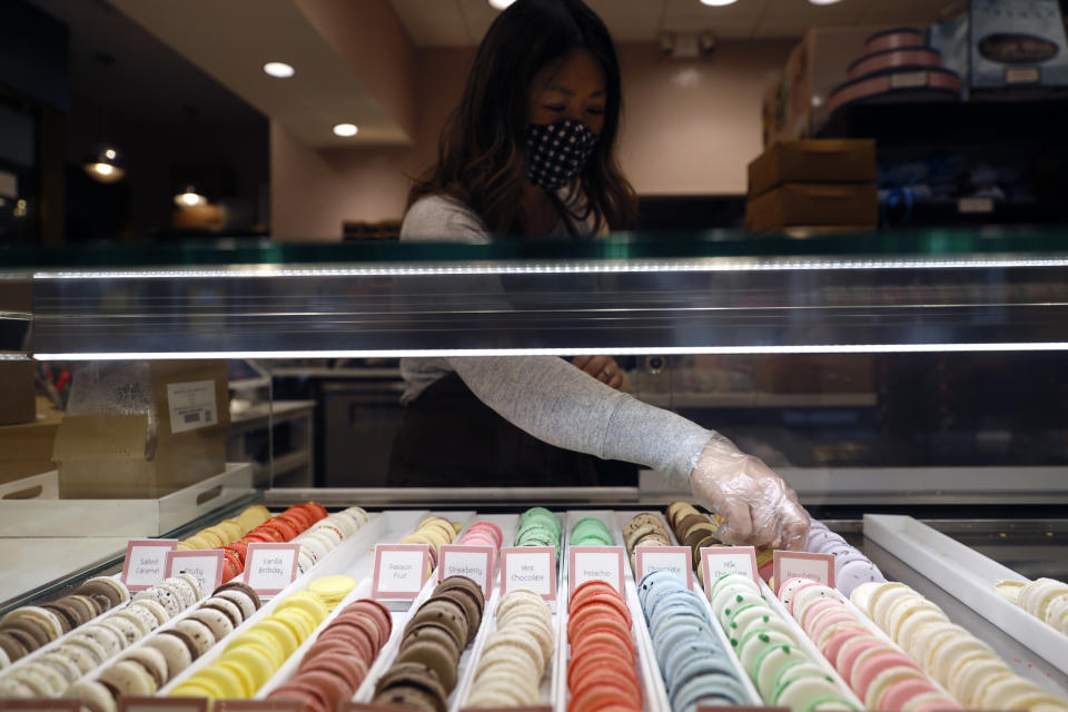 Sugar Bliss Bakery owner Teresa Ging organizes arranges bakery items in her shop in Chicago's famed Loop, Tuesday, May 4, 2021. In many downtown areas where companies closed their offices and commuting ground to a halt, sandwich shops, bakeries and other small businesses are waiting with guarded optimism for their customers to return. (AP Photo/Shafkat Anowar)