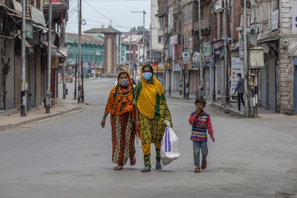 Indian women walk through a deserted road during a lockdown to curb the spread of coronavirus after collecting food item distributed as relief in Srinagar, Indian controlled Kashmir, Wednesday, May 5, 2021. (AP Photo/ Dar Yasin)