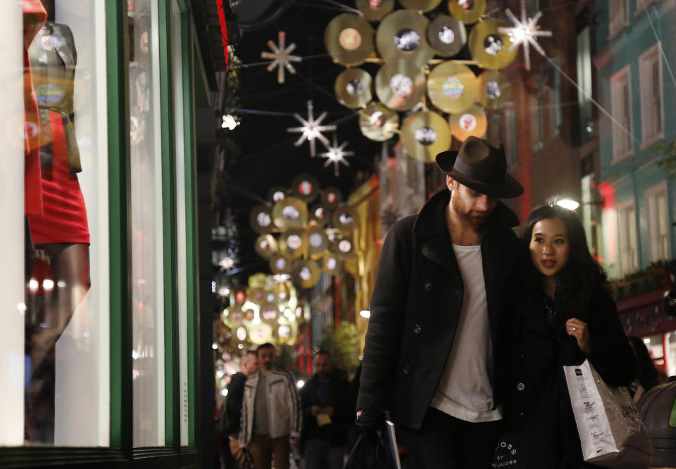 A couple walk past a shop window in London