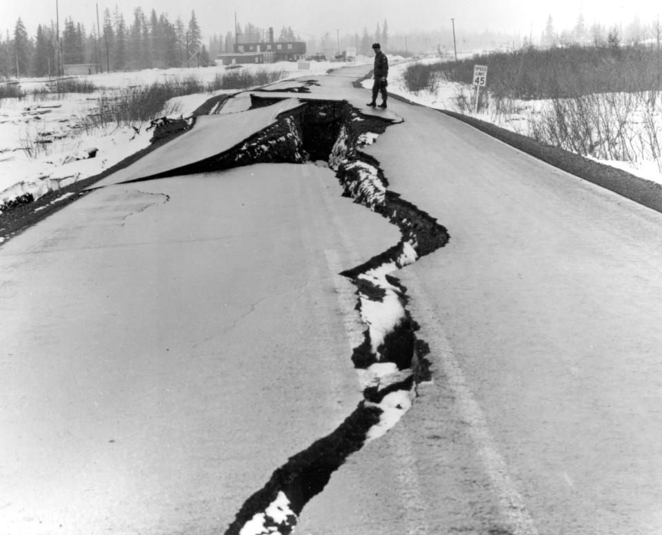 In this March 27, 1964 photo released by the U.S. Geological Suvery, a man looks over fissures following an earthquake in the Seward Highway at the head of Turnagain Arm near Anchorage, Alaska. North America's largest earthquake rattled Alaska 50 years ago, killing 15 people and creating a tsunami that killed 124 more from Alaska to California. The magnitude 9.2 quake hit at 5:30 p.m. on Good Friday, turning soil beneath parts of Anchorage into jelly and collapsing buildings that were not engineered to withstand the force of colliding continental plates. (AP Photo/U.S. Geological Survey