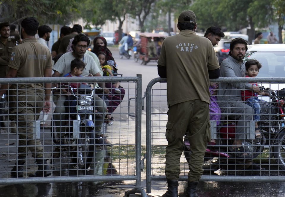 Pakistani security officials close a road outside the former Prime Minister Imran Khan's residence in Lahore, Pakistan, Friday, May 19, 2023. Khan dialed down his campaign of defiance Friday, saying he would allow a police search of his residence over allegations he was harboring suspects wanted in recent violence and appearing before a court in his hometown to seek protection from arrest in multiple terrorism cases. (AP Photo/K.M. Chaudary)