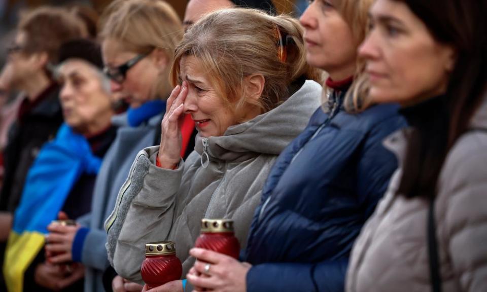 Une femme qui fait partie d'une foule d'autres personnes en tenue pour temps froid pleure 