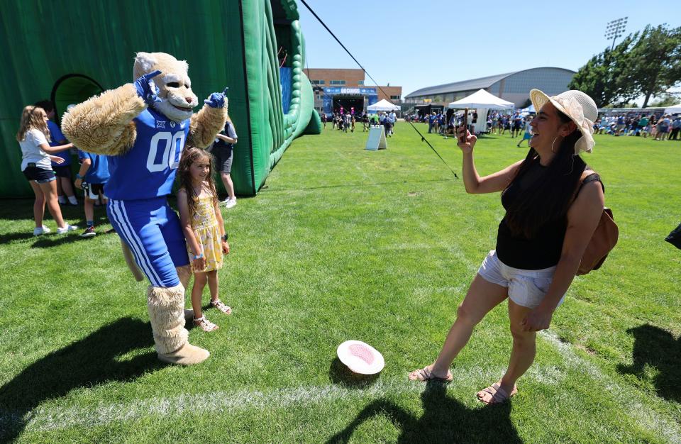 Nancy Hernandez takes a photo of her daughter Shannara Aguirre as she poses with Cosmo as BYU holds a party to celebrate their move into the Big 12 Conference with music, games and sports exhibits in Provo on Saturday, July 1, 2023. | Scott G Winterton, Deseret News