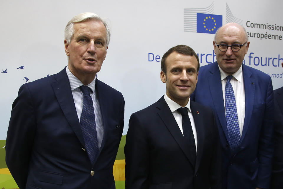 French President Emmanuel Macron, center, poses with European Union chief Brexit negotiator Michel Barnier, left, and European Commissioner for Agriculture Phil Hogan as he visits the International Agriculture Fair, in Paris, France, Saturday, Feb. 23, 2019. Macron pledged Saturday to protect European farming standards and culinary traditions threatened by aggressive foreign trade practices that see food as a "product like any other." (AP Photo/Michel Euler, Pool)