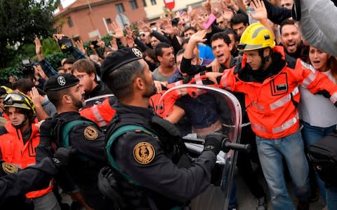 Firemen try to hold a group of people in front of Spanish Guardia Civil officers outside a polling station in San Julia de Ramis - Credit: LUIS GENE/AFP/Getty Images