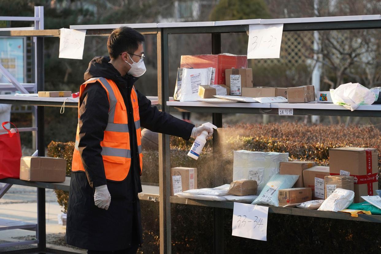 In this photo released by Xinhua News Agency, a staff member disinfects parcels at a community under close-off management where a locally transmitted COVID-19 case was found in Haidian in Beijing, China on Tuesday.