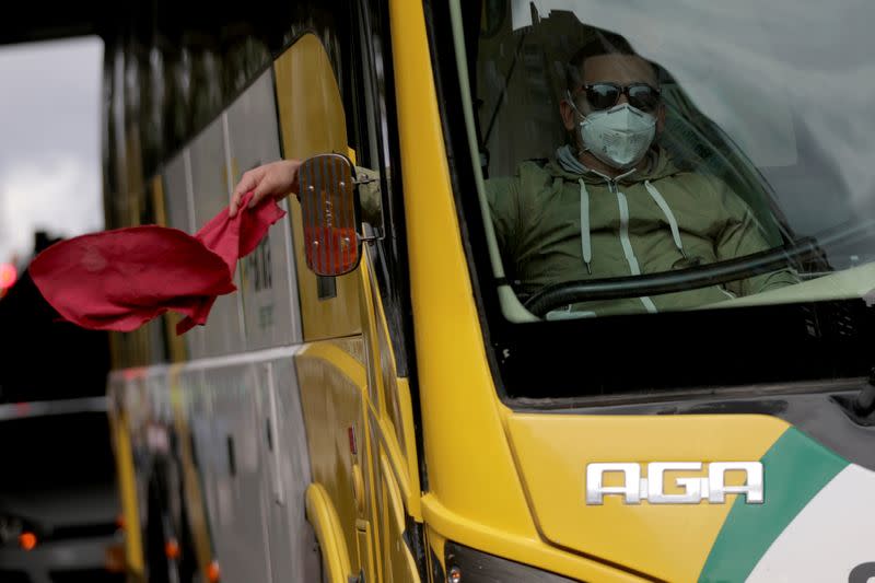 Un conductor de autobús de transporte intermunicipal usando una mascarillaondea un trapo rojo, durante una protesta para pedirle al gobierno reactivar sus trabajos, en medio del brote de COVID-19, en Bogotá, Colombia