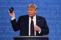 FILE - In this Sept. 29, 2020, file photo, President Donald Trump holds up his face mask during the first presidential debate at Case Western University and Cleveland Clinic, in Cleveland, Ohio. The U.S. death toll from the coronavirus has eclipsed 400,000 in the waning hours in office for Trump. (AP Photo/Julio Cortez, File)
