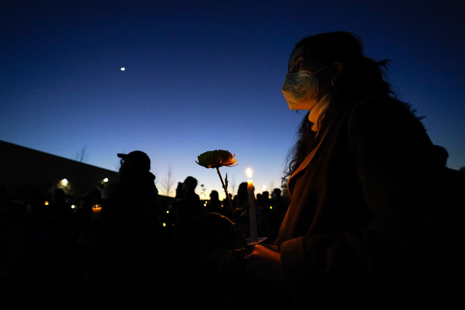 A woman holds a candle and a flower during a vigil outside Monterey Park City Hall, blocks from the Star Ballroom Dance Studio on Tuesday, Jan. 24, 2023, in Monterey Park, Calif. A gunman killed multiple people at the ballroom dance studio late Saturday amid Lunar New Years celebrations in the predominantly Asian American community. (AP Photo/Ashley Landis)