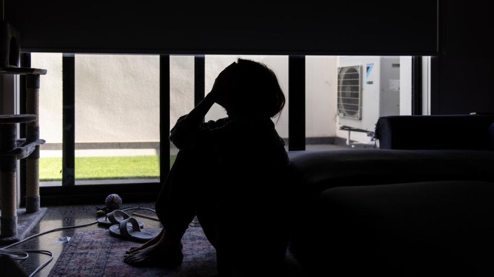 A woman sits with her head in her hands.