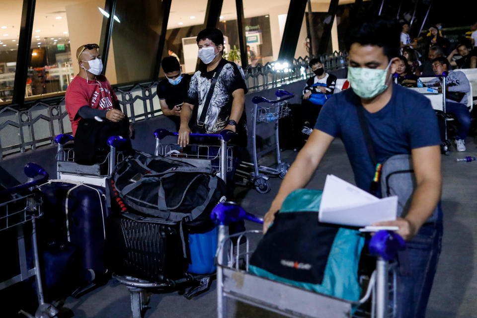 Overseas Filipino Workers (OFW) wearing protective masks stand outside the Ninoy Aquino International Airport in Pasay City, Metro Manila, Philippines, February 18, 2020. REUTERS/Eloisa Lopez