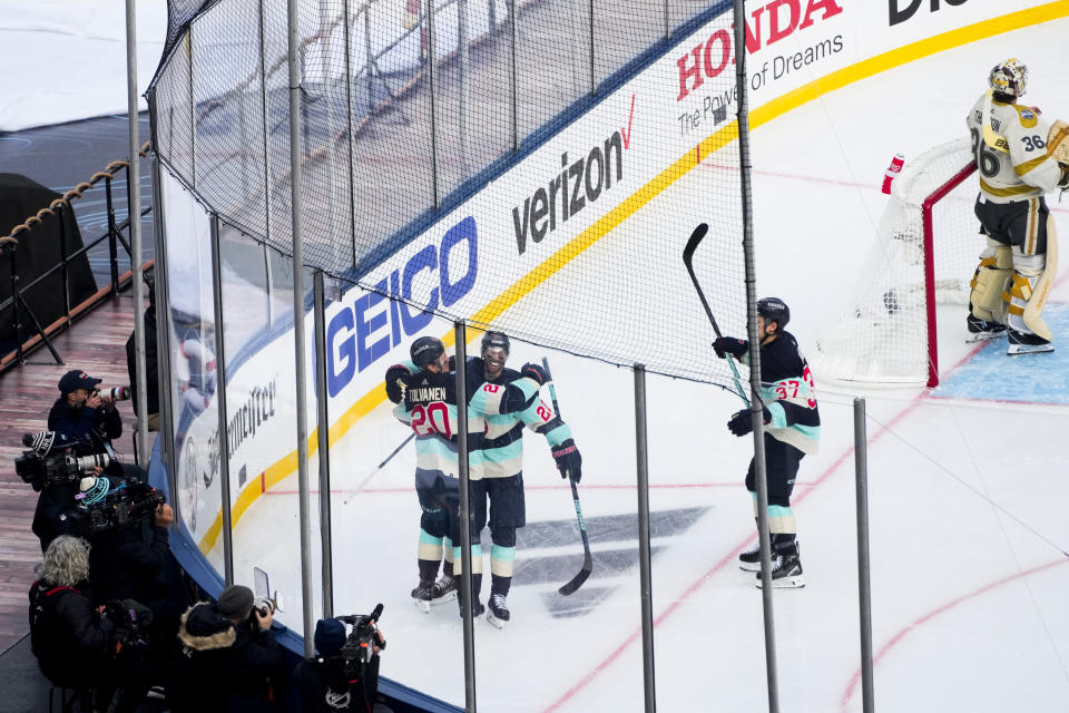 Seattle Kraken right wing Eeli Tolvanen (20) celebrates his goal with teammates right wing Oliver Bjorkstrand (22) and center Yanni Gourde (37) as Vegas Golden Knights goaltender Logan Thompson (36) looks away during the first period of the NHL Winter Classic hockey game Monday, Jan. 1, 2024, in Seattle. (AP Photo/Lindsey Wasson)