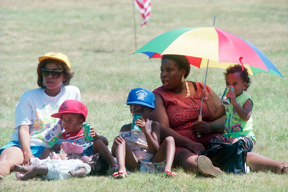 Mary Lane, second from right, sits under an umbrella with her son, Jeremy Hall, and Charity Lemma during Juneteenth activities at Hillside Park in Fort Worth in 1990.