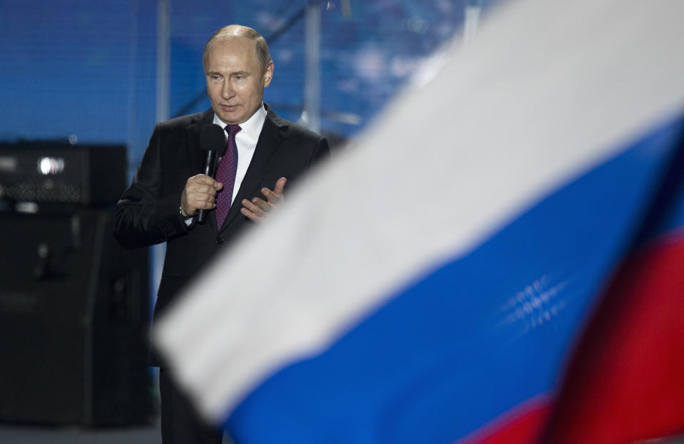 FILE - In this file photo dated Wednesday, March 14, 2018, Russian President Vladimir Putin speaks in front of a Russian National flag in Sevastopol, Crimea. An influential committee of British lawmakers plans to publish its findings Tuesday July 21, 2020, reporting on Russian interference in British politics, amid criticism the government delayed its release for more than six months to shield Prime Minister Boris Johnson and his Conservative Party from embarrassment. (AP Photo/Alexander Zemlianichenko, FILE)
