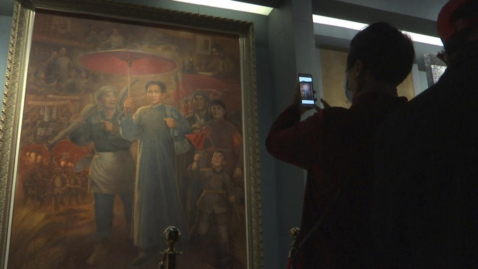 A tourist takes photos of a painting depicting the late Communist leader Mao Zedong, at the Jinggangshan Revolution Museum in Jinggangshan in southeastern China's Jiangxi province, on April 8, 2021. On the hundredth anniversary of the Chinese Communist Party, tourists in China are flocking to historic sites and making pilgrimages to party landmarks. (AP Photo/Emily Wang)