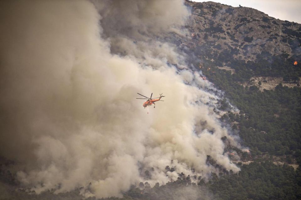 A Skycrane flies over a wildfire spreading near Archanes, north of Athens (Spyros Bakalis / AFP via Getty Images)