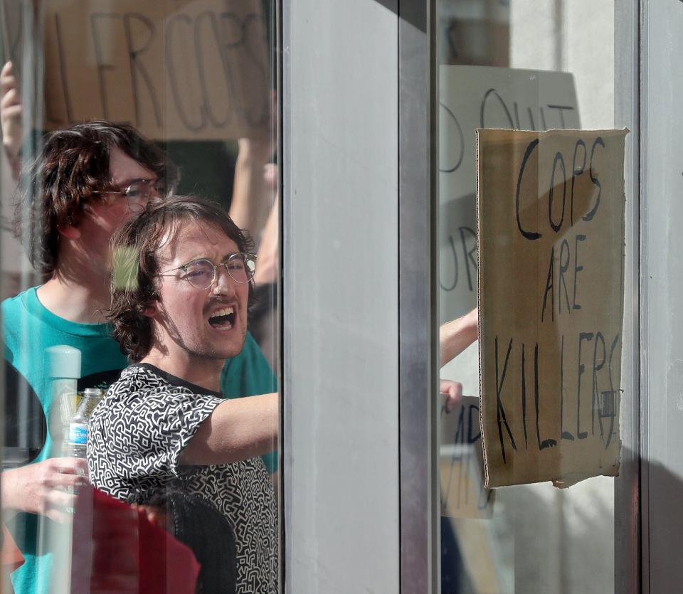 Protesters shout at police officers sitting inside the Stubbs Justice Center during Saturday's rally in downtown Akron.