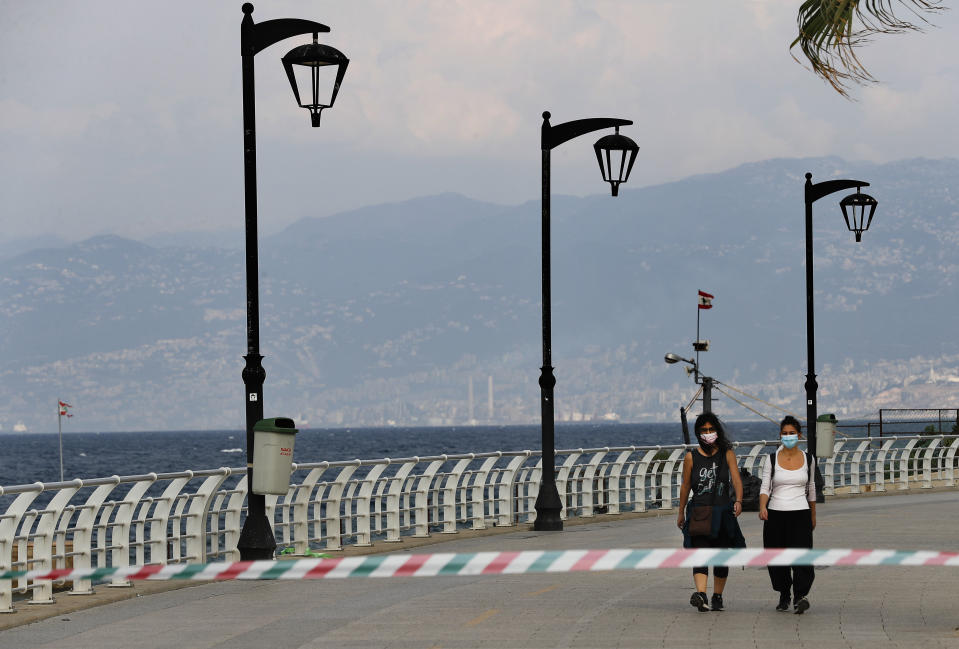 Two woman wear their masks while walking on the deserted corniche along the Mediterranean Sea, as the country began a two-week lockdown to limit the spread of coronavirus that killed dozens of people over the past days, in Beirut, Lebanon, Saturday, Nov. 14, 2020. The lockdown comes after the number cases increased sharply in recent weeks around Lebanon straining the country's medical sector where intensive care units are almost full. (AP Photo/Hussein Malla)