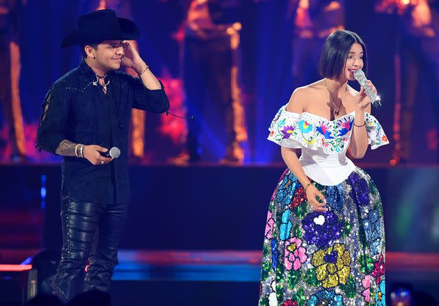 <p>Jason Koerner/Getty</p> Christian Nodal and Angela Aguilar perform on stage during Premios Juventud 2019 at Watsco Center on July 18, 2019 in Coral Gables, Florida.