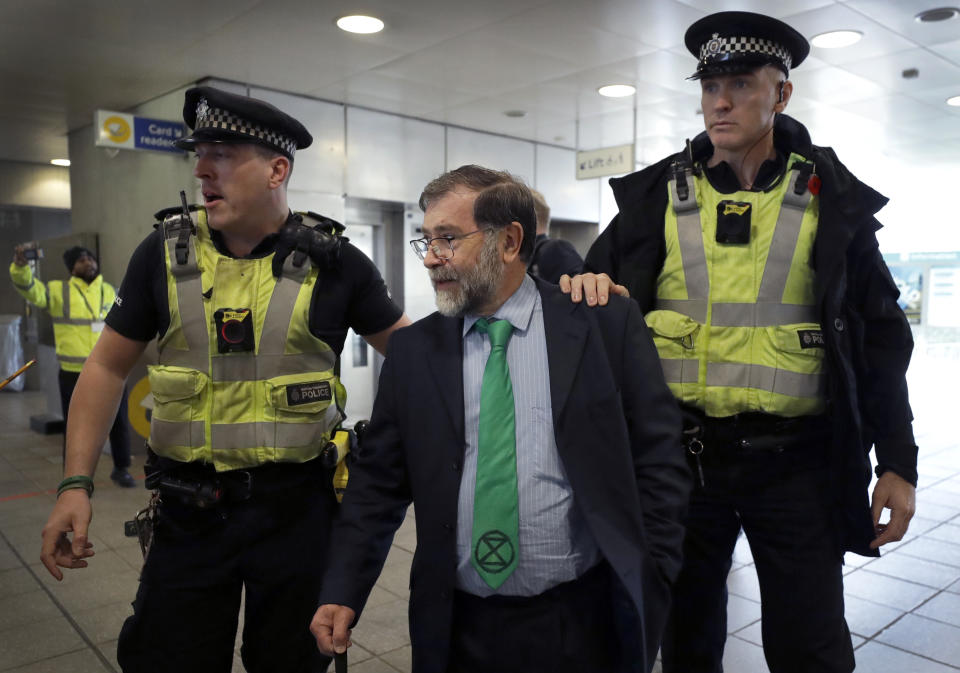 A demonstrator wearing an Extinction Rebellion tie is removed by Police Officers as demonstrators peacefully block an entrance at City Airport in London, Thursday, Oct. 10, 2019. Some hundreds of climate change activists are in London during a fourth day of world protests by the Extinction Rebellion movement to demand more urgent actions to counter global warming. (AP Photo/Matt Dunham)