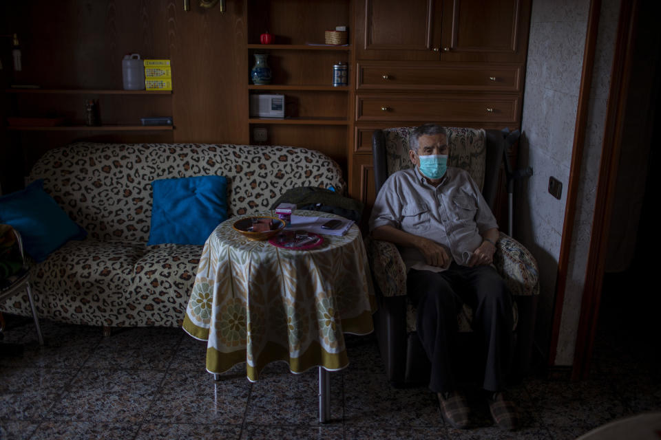 Vicente Lopez, 65, sits at his house waiting to be examined by a doctor during a home care visit in Barcelona, Spain, March 31, 2020. Lopez is under quarantine, because his partner tested positive for COVID-19 and is in the hospital. Lopez relies on a neighbor to deliver groceries and basic supplies. (AP Photo/Emilio Morenatti)