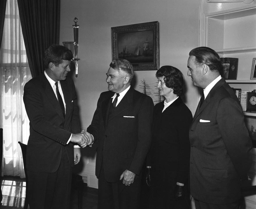 President John Kennedy shakes hands with Anthony A. Oading of Florrissant, Mo, the 15 millionth people to receive benefits under the federal Social Security program in his White House office on Feb. 27, 1961. Mrs. Oading and Secretary of Welfare Abraham Ribicoff accompanied him on the visit. Oading has just retired as a model builder for a St. Louis, MO, aircraft firm. Born in Freckenhorst, Germany, he became a naturalized U.S. citizen in 1928. (AP Photo/HWG)