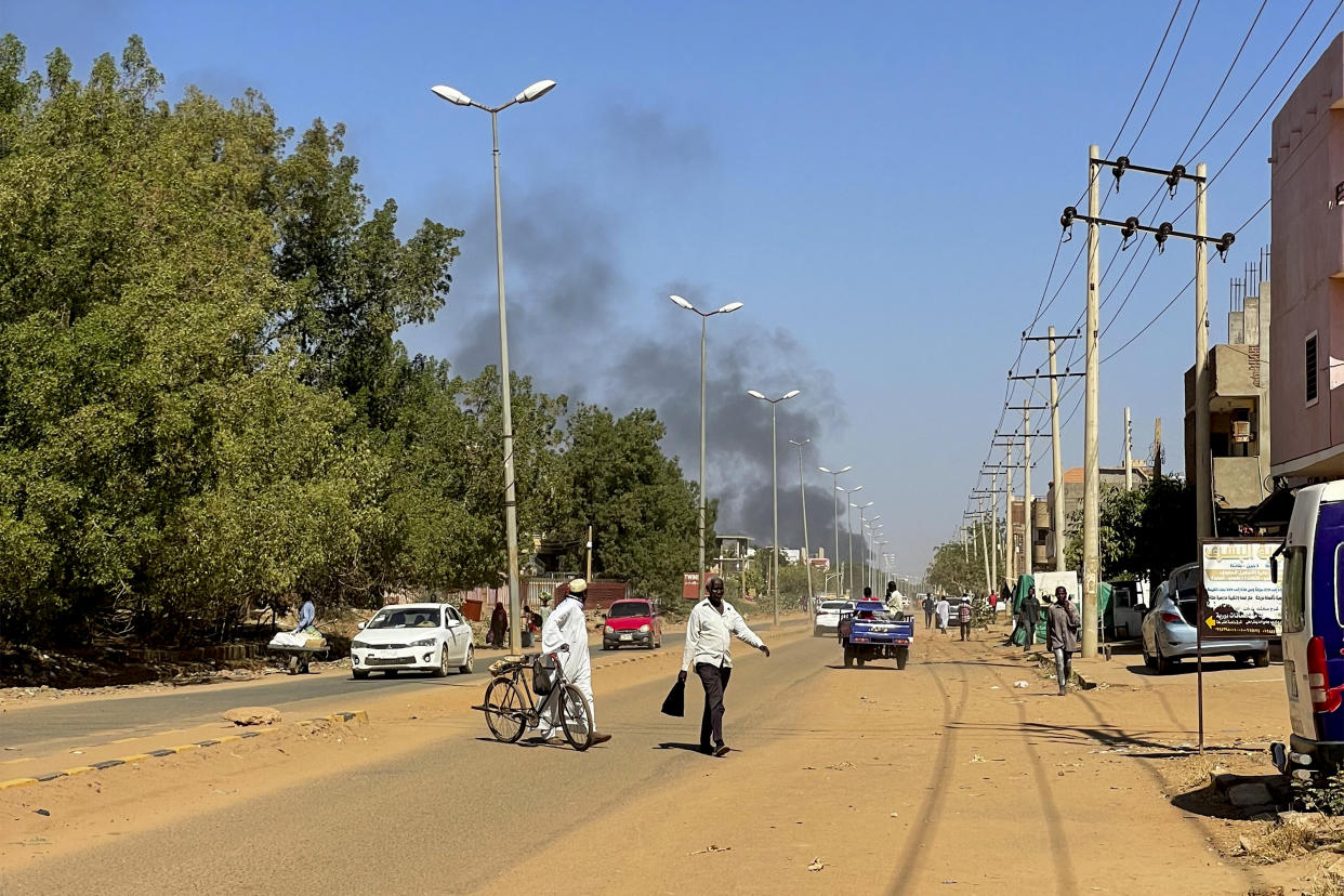 People displaced by the conflict in Sudan walk along road as smoke billows in the distance during clashes in Wad Madani, the capital of al-Jazirah state, on December 16, 2023. Fighting between the Sudanese army and paramilitaries engulfed the aid hub of Wad Madani on December 15, triggering an exodus of civilians already displaced by eight months of war, an AFP correspondent reported. When war broke out in April between the Sudanese armed forces and the paramilitary Rapid Support Forces (RSF), Wad Madani quickly became a safe haven for civilians fleeing heavy fighting in the capital Khartoum, 180 kilometres (110 miles) to the north. (Photo by AFP) (Photo by -/AFP via Getty Images)