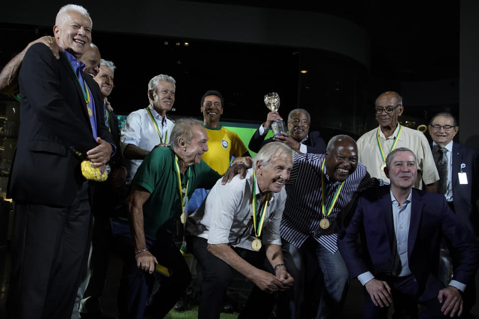 Legendary former Brazilian players and the president of the Brazilian Football Confederation Rogerio Caboclo, bottom right, pose for a photo with a statue of soccer legend Pele, at the Brazilian Soccer Team Museum in Rio de Janeiro, Brazil, Thursday, Feb. 20, 2020. The Brazilian Football Confederation unveiled the statue as part of commemorations of 50 years since the World Cup victory in 1970. (AP Photo/Leo Correa)