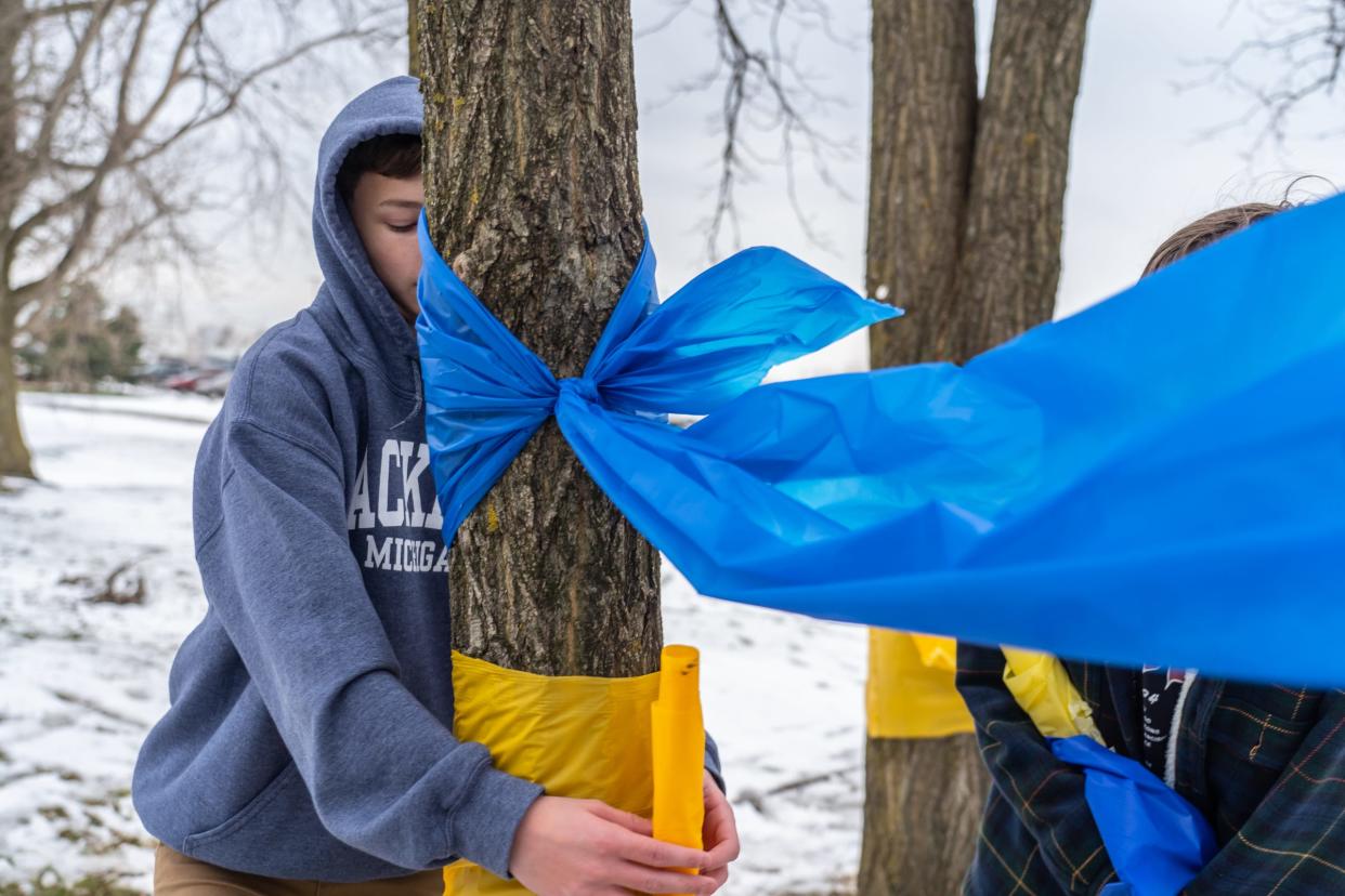 Oxford High School ninth graders Rory Metzger (left) of Oxford and Zachary Majewski of Oxford help tie ribbons around trees outside of Oxford High School on Wednesday, December 1, 2021, following an active shooter situation at Oxford High School that left four students dead and multiple others with injuries.