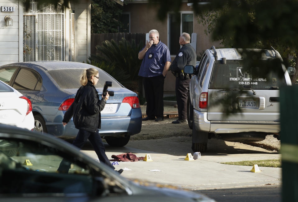 Fresno police Investigator Brooke Passmore, left, works on the driveway on Lamona Ave. where a shooting took place at a house party which involved multiple fatalities and injuries in Fresno, Calif., Monday, Nov. 18, 2019. (AP Photo/Gary Kazanjian)