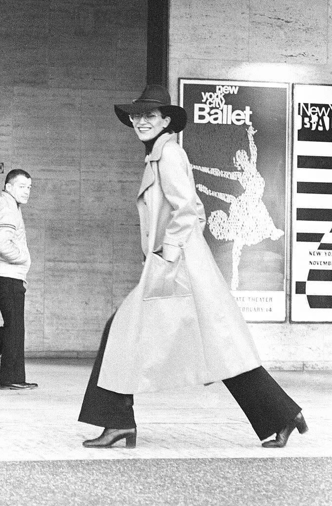 <p> Model Elsa Peretti wearing wide-leg pants with a long-length trench circa 1950. </p>