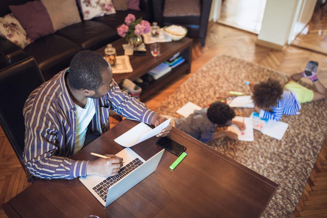 father working from home while his two children are playing in the living room