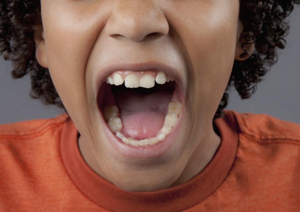 A close-up of a kid opening their mouth as if to bite something