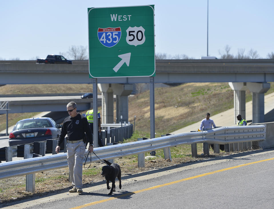 In this photo taken on Wednesday, April 9, 2014, Kansas City police and agents from the Alcohol, Tobacco and Firearms with canines investigated a shooting along southbound Interstate 435 in Kansas City, Mo. Police have connected 12 shootings targeting vehicles on Kansas City-area roads and highways since early March. Three drivers have been wounded by gunfire, though none of the wounds was considered life-threatening. (AP Photo/The Kansas City Star, Jill Toyoshiba)