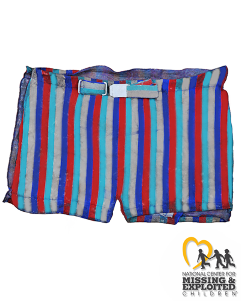 John Doe was found with belted “Catalina” swim trunks with vertical red, turquoise, gold, and dark blue stripes, with the letter “C” with golden wings on the silver buckle (National Center for Missing & Exploited Children)