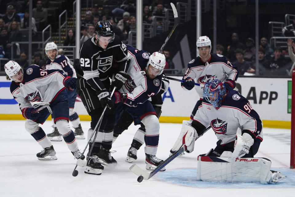 Los Angeles Kings defenseman Brandt Clarke (92) shoots against Columbus Blue Jackets goaltender Elvis Merzlikins (90) and Ivan Provorov (9) during the second period of an NHL hockey game Tuesday, Feb. 20, 2024, in Los Angeles. (AP Photo/Ryan Sun)