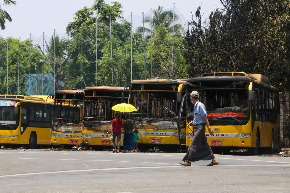 People look at a row of burnt public transport buses parked at Kyimyindaing township in Yangon, Myanmar Monday, April 12, 2021. Local news media reported that the buses got burned early Monday morning, but provided no details for the cause. (AP Photo)