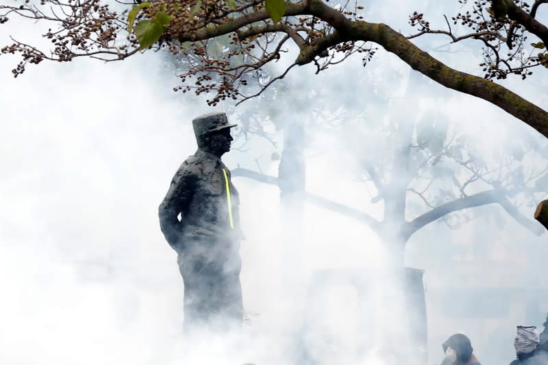The partially destroyed monument of marshal Alphonse Juin stands amidst tear gas during a demonstration to mark the first anniversary of the "yellow vests" movement in Paris