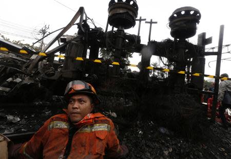 A firefighter sits near a burned gasoline truck after it collided with a commuter train at Bintaro district in Jakarta, December 9, 2013. REUTERS/Beawiharta