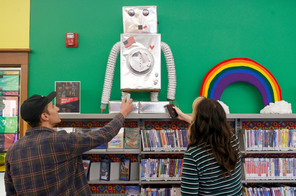 Krystian Quint, 26, left, and Jessica Doster, 28, both of Hamtramck, use K2 sensors to search for spirits in the kids section of the Redford Public Library in Redford on Saturday, Oct. 8, 2022. The sensors can pick up a spirit's energy based on the number of lights it's registering. The library invited the group to come in after hours to use their equipment to look for spirits while also allowing over 20 library visitors who had signed up earlier to go along on the search.