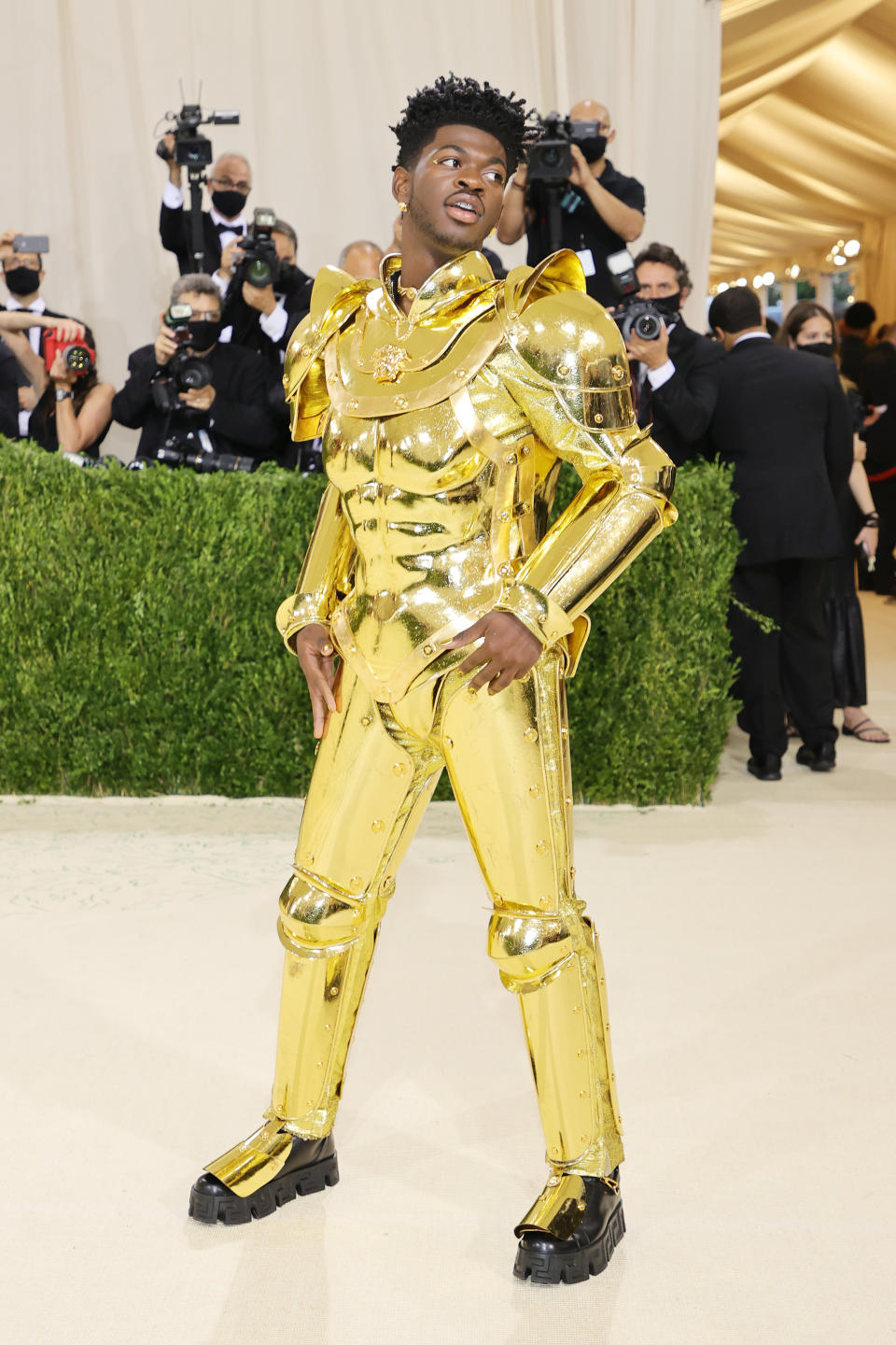 Lil Nas X in a metallic outfit resembling a futuristic robot with oversized shoulders and boots