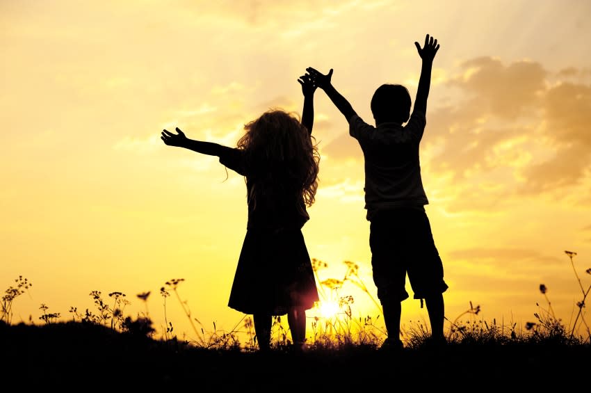 Silhouette, group of happy children playing on meadow, sunset, summertime