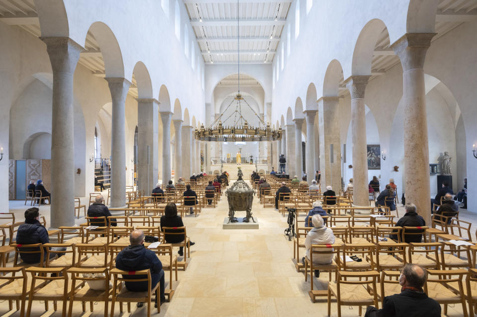 Peoplke sit at a distance from each other in the cathedral during Easter services in Hildesheim, Germany, Sunday, April 4, 2021. Despite the Corona pandemic and numerous contact restrictions, churches are allowed to celebrate numerous presence services around Easter. (Julian Stratenschulte/dpa via AP)