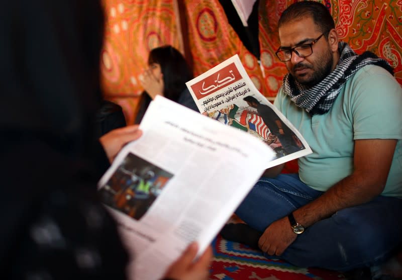 An Iraqi demonstrator reads Tuktuk newspaper during the ongoing anti-government protests, in Baghdad